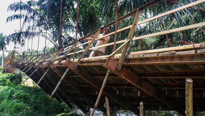 Tiga anak bergantungan di besi saat melewati jembatan gantung yang terputus di Desa Alue Keujruen, Kecamatan Tanah Luas, Aceh Utara, Aceh. Selasa (10/10/2023). Putus dan ambruknya jembatan gantung penghubung enam kecamatan tersebut dikarenakan kondisi rekontruksi tua sehingga tidak mampu menahan beban berat kenderaan roda empat yang kerap melewati jembatan tersebut. ANTARA FOTO/Rahmad/YU