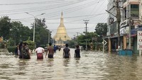 Penduduk setempat menyeberangi jalan yang terendam banjir di dekat pagoda Shwe Maw Taw di Bago, sekitar 80 kilometer (50 mil) timur laut Yangon, Myanmar, Senin (9/10/2023). Pejabat dan media pemerintah mengatakan, banjir yang dipicu oleh hujan lebat di wilayah selatan Myanmar telah menyebabkan lebih dari 14.000 orang mengungsi dan mengganggu lalu lintas di jalur kereta api yang menghubungkan kota-kota terbesar di negara itu.
