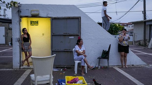 Israelis stay nearby a public bomb shelter, to stay safe from rockets fired from Gaza Strip towards Israel, in the southern Israeli city of Ashkelon, Sunday, Oct. 8, 2023. The militant Hamas rulers of the Gaza Strip carried out an unprecedented, multi-front attack on Israel at daybreak Saturday, firing thousands of rockets as dozens of Hamas fighters infiltrated the heavily fortified border in several locations, killing hundreds and taking captives. Palestinian health officials reported scores of deaths from Israeli airstrikes in Gaza. (AP Photo/Ohad Zwigenberg)