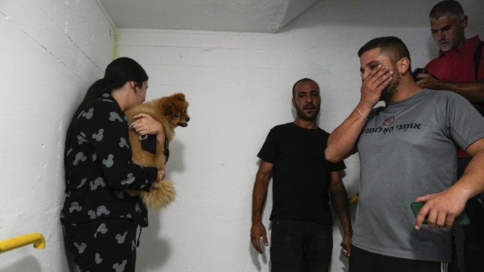 Israelis stay nearby a public bomb shelter, to stay safe from rockets fired from Gaza Strip towards Israel, in the southern Israeli city of Ashkelon, Sunday, Oct. 8, 2023. The militant Hamas rulers of the Gaza Strip carried out an unprecedented, multi-front attack on Israel at daybreak Saturday, firing thousands of rockets as dozens of Hamas fighters infiltrated the heavily fortified border in several locations, killing hundreds and taking captives. Palestinian health officials reported scores of deaths from Israeli airstrikes in Gaza. (AP Photo/Ohad Zwigenberg)