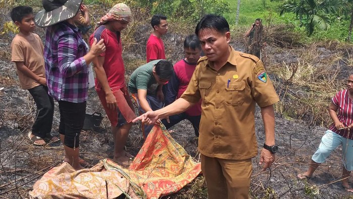 Warga mengevakuasi jasad korban, Syaf (57) yang terbakar usai terjebak di lahan yang dibukanya. (istimewa)