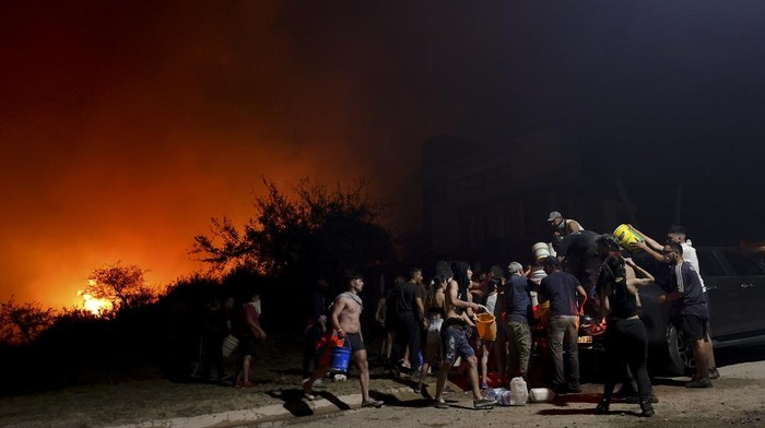 A firefighter is silhouetted by the flames of a forest fire on the outskirts of Villa Carlos Paz, Argentina, Tuesday, Oct. 10, 2023. (AP Photo/Nicolas Aguilera)