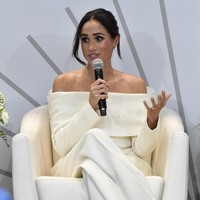 Meghan Markle memakai blazer dari koleksi Altuzzara yang dipadukan dengan celana panjang putih berpotongan lebar serta high heels model slingback. Foto: AP/Evan Agostini