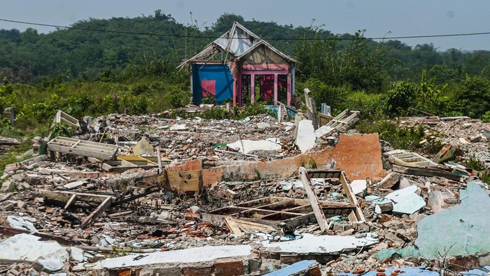 Seorang ibu bersama anaknya berjalan di sekitar rumah yang sudah ditinggali pemiliknya di Kampung Karian, Lebak, Banten.