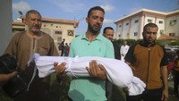 Seorang kerabat membawa jenazah anak kecil, yang tewas dalam serangan udara Israel, saat pemakamannya di Khan Younis, Jalur Gaza. AP/Hatem Ali