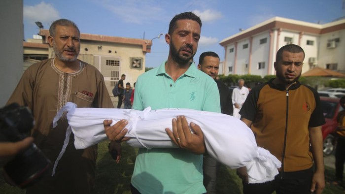 A relative carries the body of Amir Ganan, who was killed in an Israeli airstrike, during his funeral in Khan Younis, Gaza Strip, Tuesday, Oct. 10, 2023. (AP Photo/Hatem Ali)