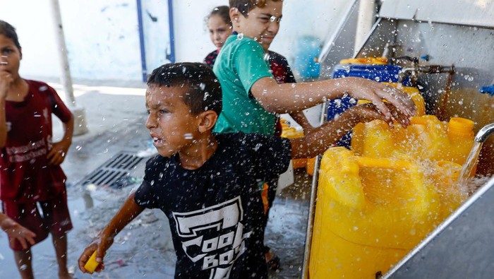 Potret Warga Gaza Antre Air di Tengah Blokade Israel People stand next to containers as Palestinians gather to fill water from public taps amid the conflict with Israel in Khan Younis, in the southern Gaza Strip, October 11, 2023. REUTERS/Ibraheem Abu Mustafa