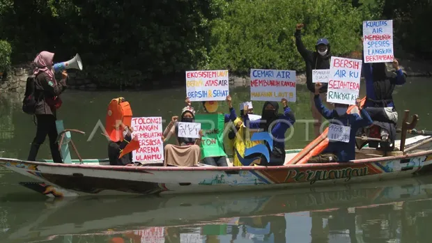 Aktivis lingkungan dari Muhammadiyah Pecinta Alam Semesta (Mupalas) membentangkan poster saat menggelar aksi teatrikal memperingati Hari Air Sedunia di sekitar muara Sungai Tambak Wedi, Surabaya, Jawa Timur, Senin (22/3/2021)
