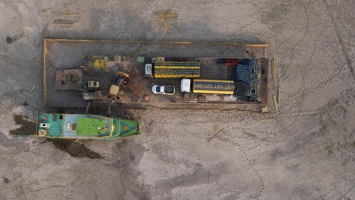 Penampakan Kapal Tongkang Terdampar di Sungai Amazon yang Mengering A tug boat and a barge carrying three trucks, 2,000 empty cooking gas cylinders and a backhoe, lie stranded on a sand bank of a diminished Rio Negro river after running aground last month, as the region is hit by a severe drought, in Cacau Pirera, Brazil October 10, 2023. REUTERS/Bruno Kelly