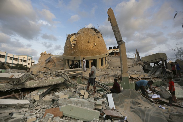 People stand outside a mosque destroyed in an Israeli air strike in Khan Younis, Gaza Strip, Sunday, Oct.8, 2023. The Hamas militants broke out of the blockaded Gaza Strip and rampaged through nearby Israeli communities, taking captives, while Israels retaliation strikes leveled buildings in Gaza. (AP Photo/Yousef Masoud)