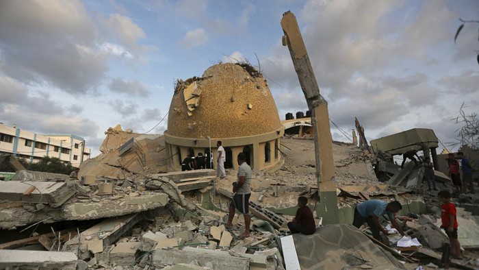 People stand outside a mosque destroyed in an Israeli air strike in Khan Younis, Gaza Strip, Sunday, Oct.8, 2023. The Hamas militants broke out of the blockaded Gaza Strip and rampaged through nearby Israeli communities, taking captives, while Israels retaliation strikes leveled buildings in Gaza. (AP Photo/Yousef Masoud)