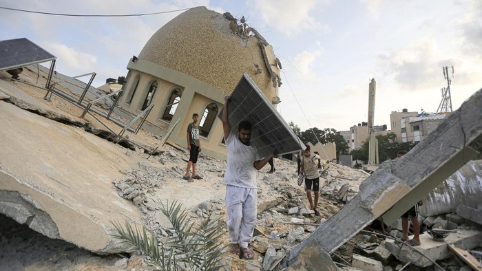 People stand outside a mosque destroyed in an Israeli air strike in Khan Younis, Gaza Strip, Sunday, Oct.8, 2023. The Hamas militants broke out of the blockaded Gaza Strip and rampaged through nearby Israeli communities, taking captives, while Israel's retaliation strikes leveled buildings in Gaza. (AP Photo/Yousef Masoud)