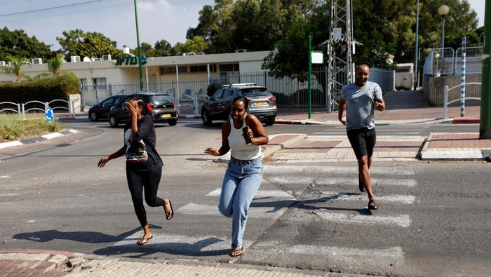 An Israeli military reservist helps residents of Ashkelon evacuate the city as he holds a rocket that was launched from the Gaza Strip and landed in Ashkelon, southern Israel, October 11, 2023. REUTERS/Amir Cohen     TPX IMAGES OF THE DAY