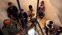 Orang-orang berlindung di tangga gedung saat sirene berbunyi saat roket dari Gaza diluncurkan ke Israel, di Ashkelon, Israel selatan, 10 Oktober 2023.  