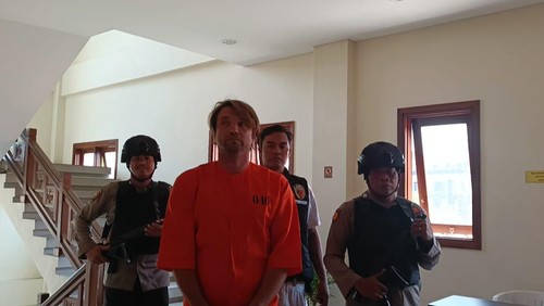 Polisi menggiring warga negara (WN) Rusia Grigori Krasnoshtanov ke ruang tahanan di Polsek Kuta Selatan, Jumat (13/10/2023).