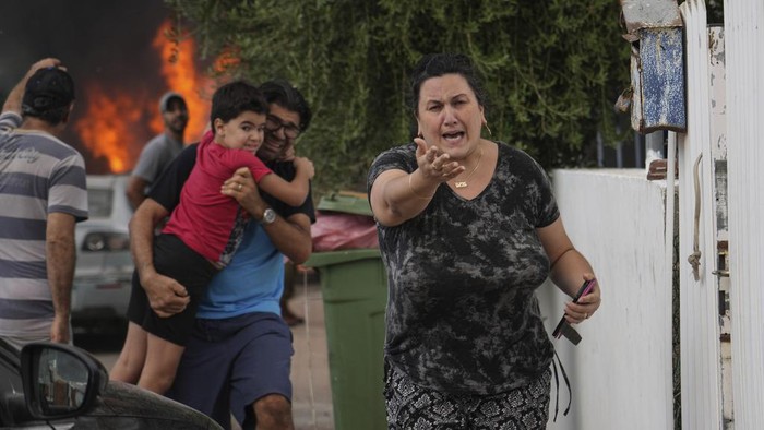 Israelis evacuate a site struck by a rocket fired from the Gaza Strip, in Ashkelon, southern Israel, Monday, Oct. 8, 2023. (AP Photo/Tsafrir Abayov)