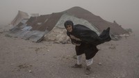 Para korban gempa ini berusaha mencari tempat berlindung dari badai pasir setelah gempa menghancurkan rumah mereka.  