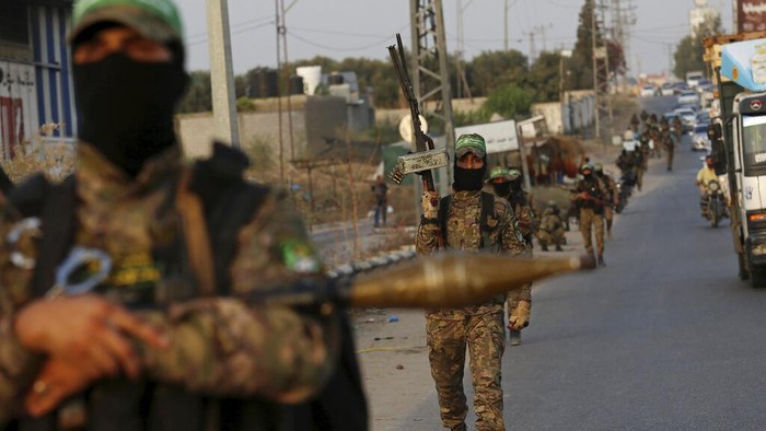 Masked militant from the Izzedine al-Qassam Brigades, the military wing of Hamas, waves the green flag of the Islamist group during a protest in support of Palestinian prisoners in Israeli jails, after Friday prayer in Nusseirat refugee camp, central Gaza Strip, Friday, Aug. 18, 2023. A thousand prisoners in Israeli jails started a mass hunger strike Friday in protest over harsh new Israeli prison measures. (AP Photo/Adel Hana)