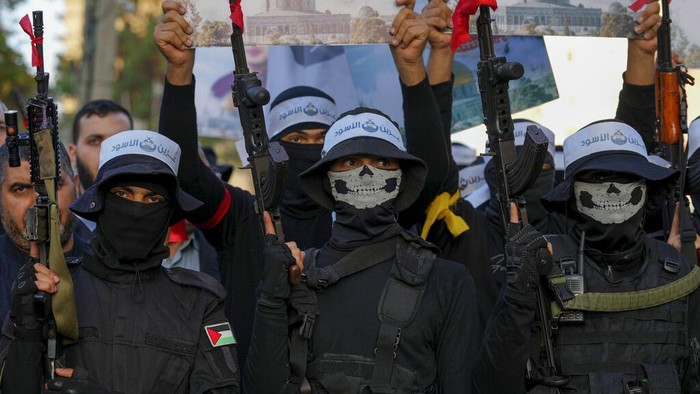 Masked militant from the Izzedine al-Qassam Brigades, the military wing of Hamas, waves the green flag of the Islamist group during a protest in support of Palestinian prisoners in Israeli jails, after Friday prayer in Nusseirat refugee camp, central Gaza Strip, Friday, Aug. 18, 2023. A thousand prisoners in Israeli jails started a mass hunger strike Friday in protest over harsh new Israeli prison measures. (AP Photo/Adel Hana)