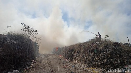 Petugas pemadam kebakaran sedang menyemprotkan air ke kobaran api pada tumpukan sampah di TPA Mandung, Sabtu (14/10/2023).