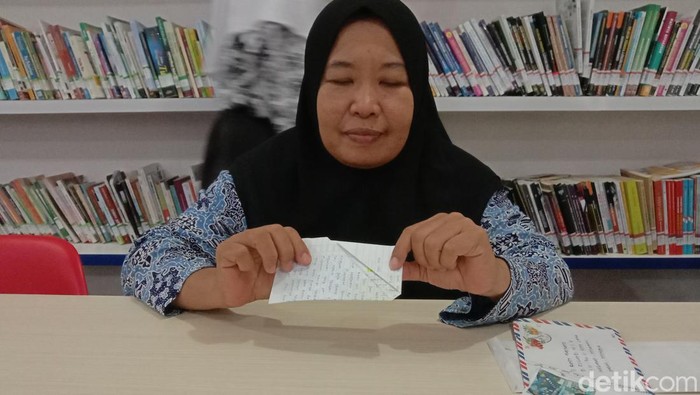 Ucih menunjukkan cara melipat surat yang khas sebelum dikirim lewat kantor pos