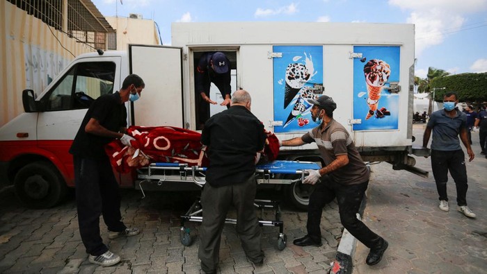 ISRAEL-PALESTINIANS/ Medical personnel works on carrying the bodies of Palestinians, who were killed in Israeli strikes, from an ice cream truck where they were kept, as the hospital morgues are packed, amid the ongoing Israeli-Palestinian conflict, in the central Gaza Strip October 15, 2023. REUTERS/Stringer