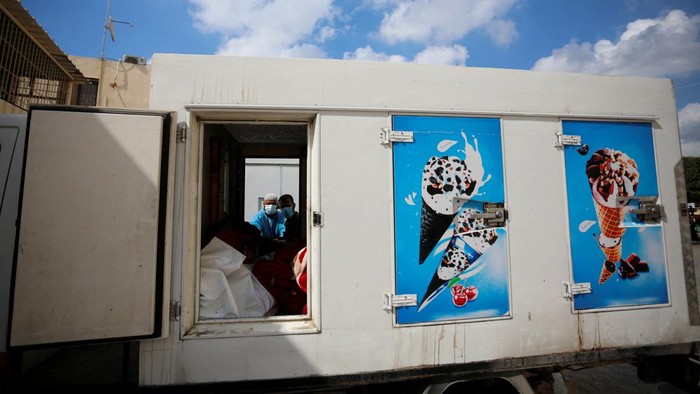 Medical personnel works on carrying the bodies of Palestinians, who were killed in Israeli strikes, from an ice cream truck where they were kept, as the hospital morgues are packed, amid the ongoing Israeli-Palestinian conflict, in the central Gaza Strip October 15, 2023. REUTERS/Stringer