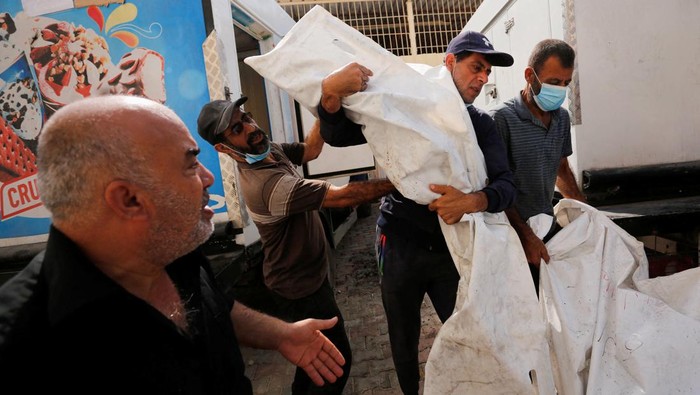ISRAEL-PALESTINIANS/ Medical personnel works on carrying the bodies of Palestinians, who were killed in Israeli strikes, from an ice cream truck where they were kept, as the hospital morgues are packed, amid the ongoing Israeli-Palestinian conflict, in the central Gaza Strip October 15, 2023. REUTERS/Stringer