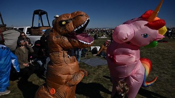 Lalu ada yang lucu. Contohnya seperti dua orang ini yang melihat gerhana menggunakan kostum unicorn dan dinosaurus di Albuquerque International Balloon Fiesta ke-51 di New Mexico, Amerika. Foto: (Patrick T. Fallon/AFP/Getty Images).