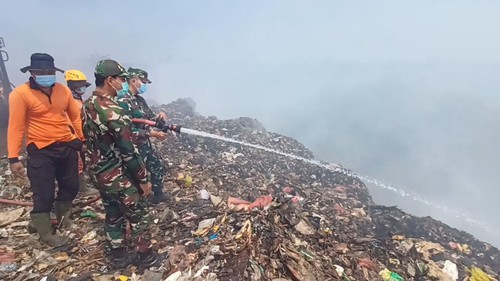 Anggota Pemadam Kebakaran, BPBD, dan tentara berupaya mendingingkan tumpukan sampah setelah terbakar di TPA Mandung, Tabanan, Bali, pada Minggu (15/10/2023).