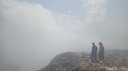 Tiga orang petugas dari TNI, Damkar, dan BPBD Tabanan menyiram tumpukan sampah di salah satu sudut TPA Mandung, Tabanan, yang masih mengeluarkan asap, Minggu (15/10/2023). (Chairul Amri Simabur/detikBali)