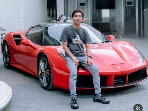 Dadang berpose di depan mobil Ferrari berwarna merah miliknya