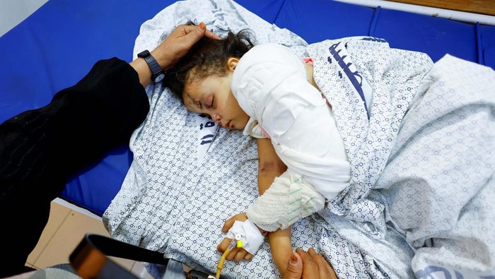 Duka Gadis Cilik Palestina yang Kehilangan 14 Anggota Keluarganya Palestinian girl Fulla Al-Laham, 4, who was wounded in an Israeli strike that killed 14 family members, including her parents and all her siblings, lies on a bed as her grandmother sits next to her, at a hospital in Khan Younis in the southern Gaza Strip, October 14, 2023. REUTERS/Mohammed Salem