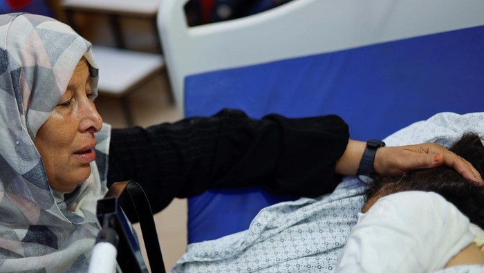 Palestinian girl Fulla Al-Laham, 4, who was wounded in an Israeli strike that killed 14 family members, including her parents and all her siblings, lies on a bed as her grandmother sits next to her, at a hospital in Khan Younis in the southern Gaza Strip, October 14, 2023. REUTERS/Mohammed Salem