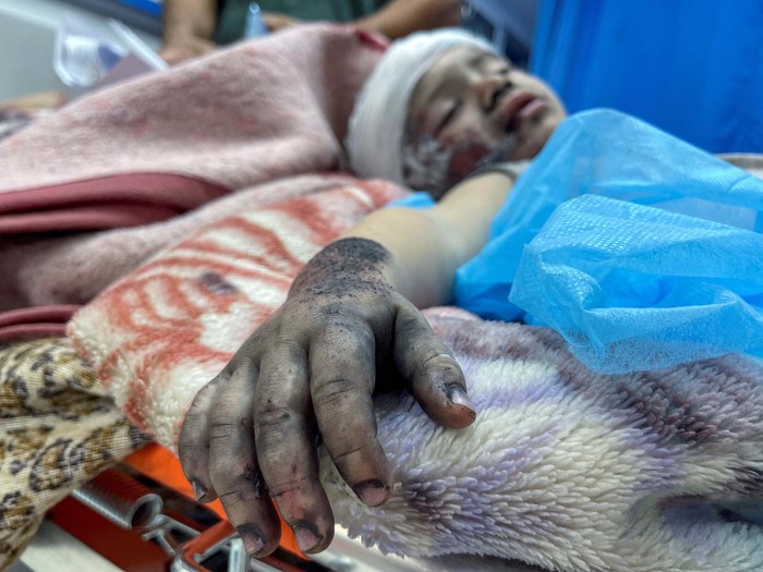 A Palestinian woman reacts next to a girl who was wounded in an Israeli strike, at Shifa hospital in Gaza City, October 15, 2023. REUTERS/Mohammed al-Masri