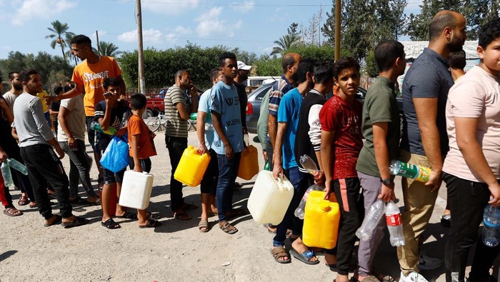 Palestinians queue as they wait to fill cans with fuel, amid shortages of fuel, as the Israeli-Palestinian conflict continues, at a petrol station in Khan Younis in the southern Gaza Strip October 15, 2023. REUTERS/Ibraheem Abu Mustafa     TPX IMAGES OF THE DAY