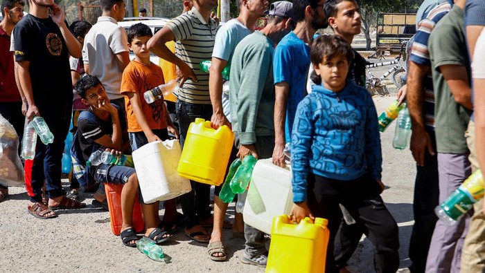 Palestinians queue as they wait to fill cans with fuel, amid shortages of fuel, as the Israeli-Palestinian conflict continues, at a petrol station in Khan Younis in the southern Gaza Strip October 15, 2023. REUTERS/Ibraheem Abu Mustafa TPX IMAGES OF THE DAY