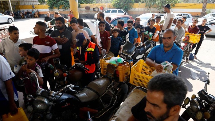 Palestinians queue as they wait to fill cans with fuel, amid shortages of fuel, as the Israeli-Palestinian conflict continues, at a petrol station in Khan Younis in the southern Gaza Strip October 15, 2023. REUTERS/Ibraheem Abu Mustafa     TPX IMAGES OF THE DAY