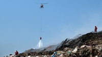 Helikopter Badan Nasional Penanggulangan Bencana (BNPB) dan sejumlah petugas pemadam kebakaran berupaya memadamkan sisa api kebakaran sampah di Tempat Pembuangan Akhir (TPA) Regional Sarbagita Suwung, Denpasar, Bali, Senin (16/10/2023). 