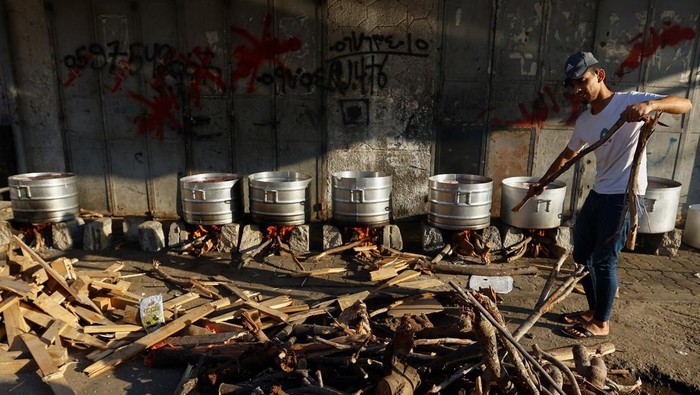 Krisis BBM, Warga Gaza Masak dengan Kayu Bakar People cook on firewood amid shortages of fuel and gas to provide food for Palestinians who fled their houses amid Israeli strikes in Khan Younis, in the southern Gaza Strip October 15, 2023. REUTERS/Ibraheem Abu Mustafa
