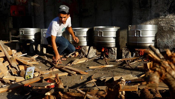 People cook on firewood amid shortages of fuel and gas to provide food for Palestinians who fled their houses amid Israeli strikes in Khan Younis, in the southern Gaza Strip October 15, 2023. REUTERS/Ibraheem Abu Mustafa