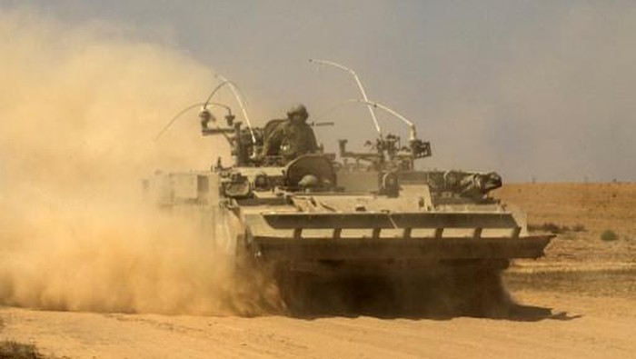 An Israeli soldier sitting atop an armoured personnel carrier (APC) rolls back into Israel from the Gaza Strip at the Sufa crossing following a military operation, 11 December 2007. Six Palestinian fighters were killed in Israel's largest operation for months against the Gaza Strip today, the eve of the first Israeli-Palestinian peace negotiations since a US summit. AFP PHOTO/JACK GUEZ (Photo by JACK GUEZ / AFP)