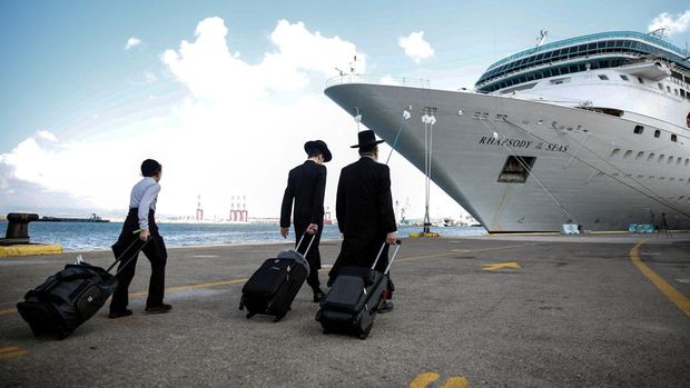 Orang-orang Yahudi ultra-Ortodoks membawa barang-barang mereka sebelum menaiki kapal untuk warga negara AS dan anggota keluarga dekat mereka ketika mereka meninggalkan Israel menuju Siprus, di tengah konflik yang sedang berlangsung antara Israel dan kelompok Islam Palestina Hamas, di Haifa, Israel, 16 Oktober 2023 . (REUTERS/Shir Torem)