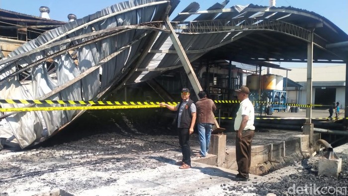 Polisi memasang garis polisi di pabrik kayu PT Nankai Gresik yang terbakar.