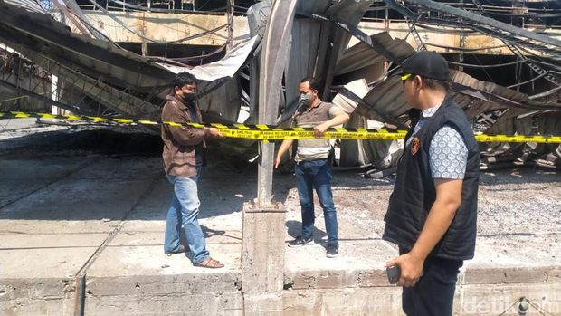 Polisi memasang garis polisi di pabrik kayu PT Nankai Gresik yang terbakar.