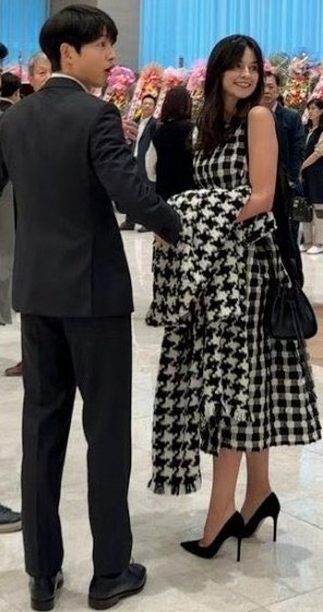 Dalam kesempatan itu, Song Joong Ki tampak gagah memakai setelan jas hitam. Sedangkan istrinya, Katy Louise Saunders memesona dalam balutan dress bermotif kotak-kotak yang senada dengan coat-nya.Foto: dok. Twitter @sjkwings1985, dok. Twitter @sang_nihal