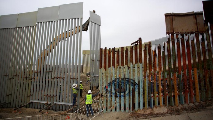People observe a construction crew working in the replacement of the corroded primary border wall between Mexico and U.S., as seen from Playas de Tijuana, Mexico October 16, 2023. REUTERS/Jorge Duenes