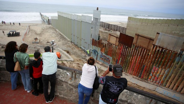 People observe a construction crew working in the replacement of the corroded primary border wall between Mexico and U.S., as seen from Playas de Tijuana, Mexico October 16, 2023. REUTERS/Jorge Duenes