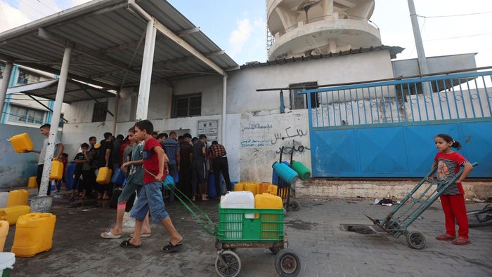 Krisis Air Melanda Warga Gaza Akibat Israel Blokade Akses Palestinian children collect water, amid the ongoing Israeli-Palestinian conflict in Khan Younis in the southern Gaza Strip, October 14, 2023. REUTERS/Ahmed Zakot