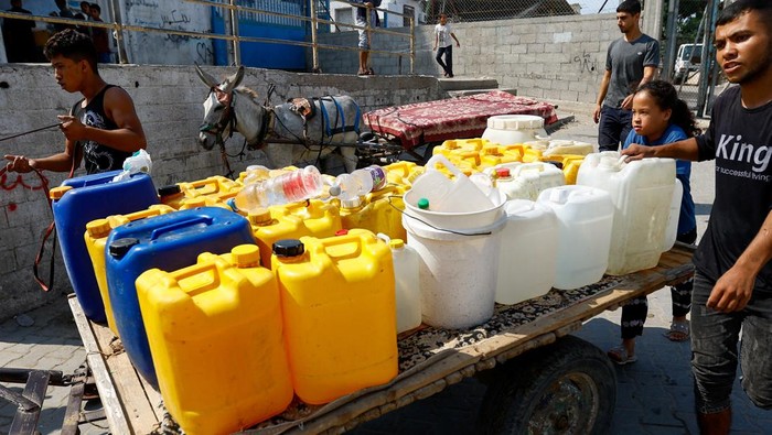 Krisis Air Melanda Warga Gaza Akibat Israel Blokade Akses A man stands next to containers as Palestinians gather to fill water from public taps amid the conflict with Israel in Khan Younis, in the southern Gaza Strip, October 11, 2023. REUTERS/Ibraheem Abu Mustafa